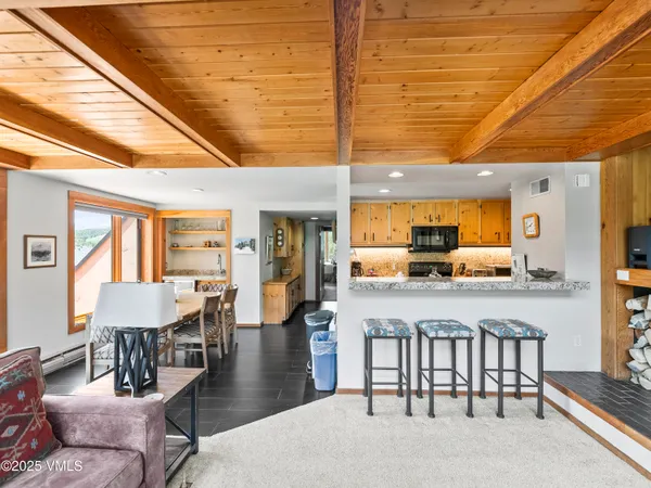 a dining hall with stainless steel appliances kitchen island granite countertop a table chairs and a refrigerator