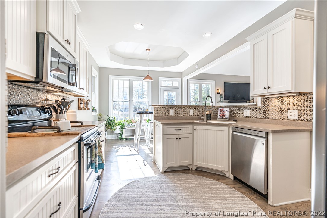 1163 Rays Bridge Road Whispering Pines, NC 28327 - Photo 11 of 37 a kitchen with stainless steel appliances granite countertop a stove top oven a sink dishwasher a dining table and chairs with wooden floor