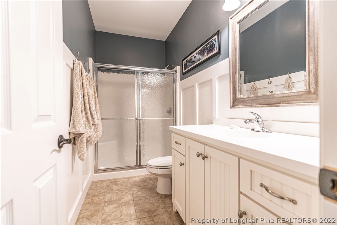 1163 Rays Bridge Road Whispering Pines, NC 28327 - Photo 23 of 37 a bathroom with a sink a toilet and a large mirror