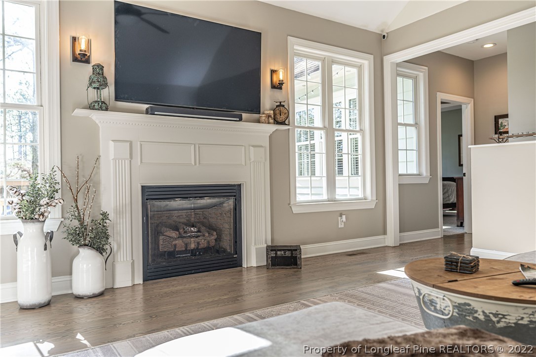 1163 Rays Bridge Road Whispering Pines, NC 28327 - Photo 8 of 37 a living room with furniture a flat screen tv and a fireplace