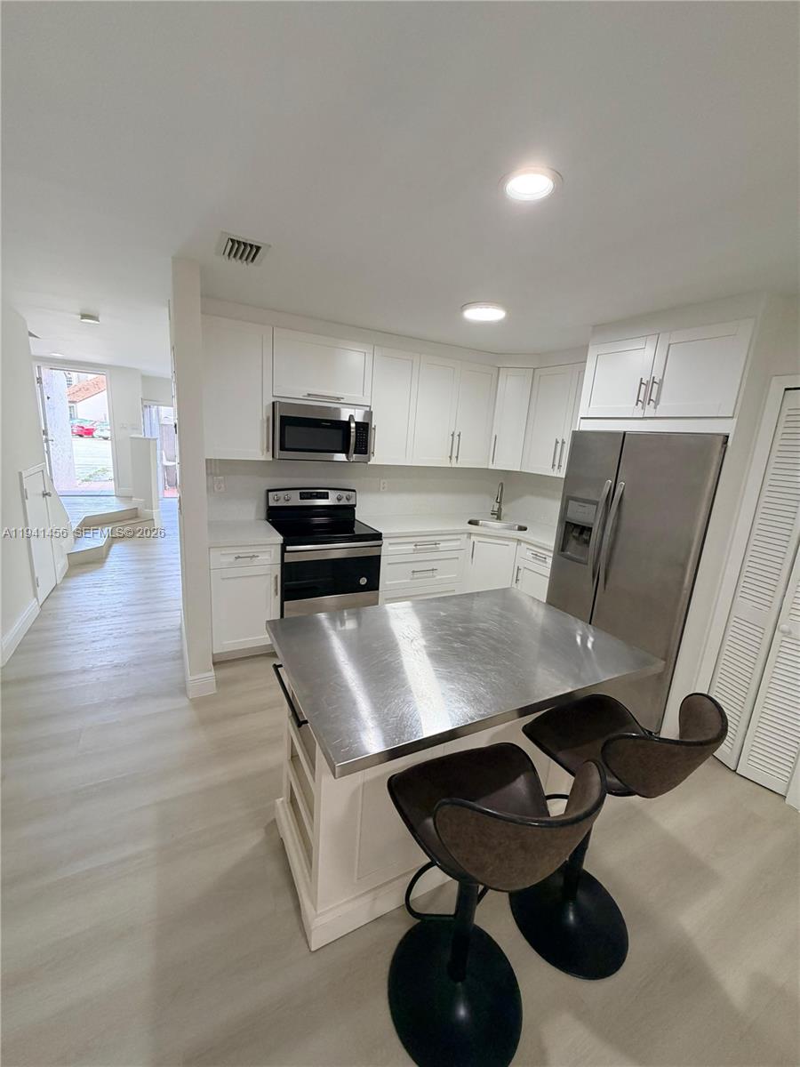 6514 Southwest 128th Place, Unit 6514 Miami, FL 33183 - Photo 7 of 18 a kitchen with cabinets and chairs