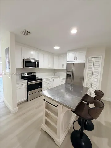 a kitchen with stainless steel appliances kitchen island granite countertop a sink dishwasher stove and refrigerator