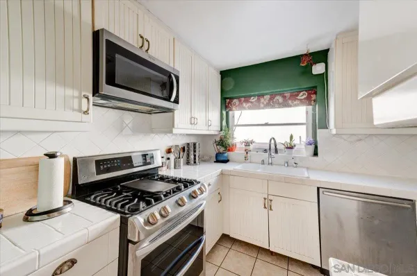 a kitchen with cabinets a window and stainless steel appliances