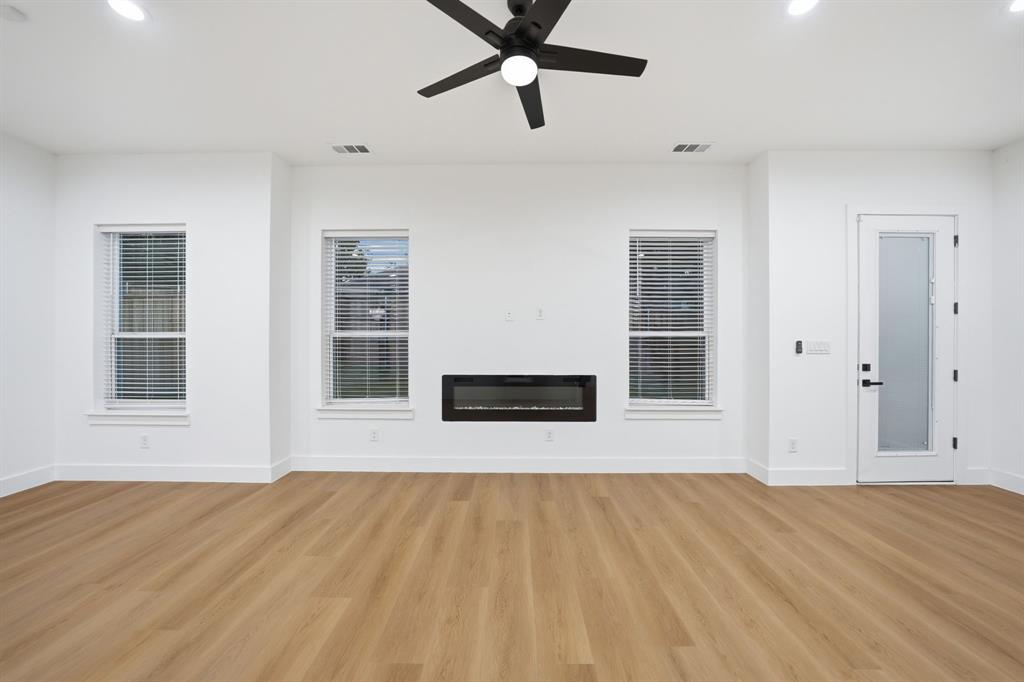 306 East 7th Street Dallas, TX 75203 - Photo 6 of 22 Spacious interior featuring wood-finish flooring, an electric fireplace, a black ceiling fan, recessed lighting, and a door with frosted glass paneling