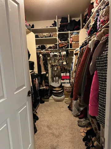 a view of walk in closet with clothes and shoes