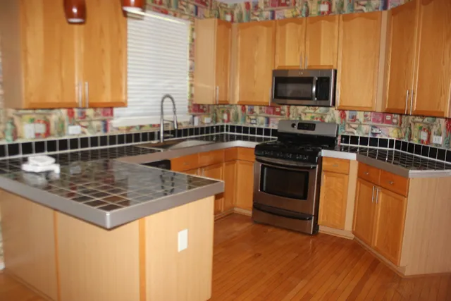 a kitchen with sink a microwave a stove and cabinets