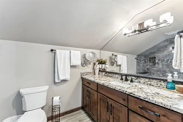 a bathroom with a granite countertop sink a toilet and mirror