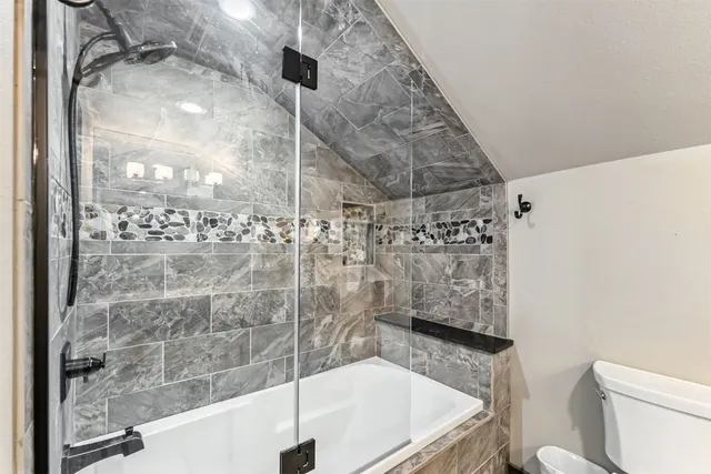 a bathroom with a granite countertop bathtub shower and toilet
