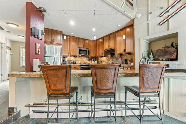 a room with stainless steel appliances kitchen island granite countertop a stove a sink a dining table and chairs