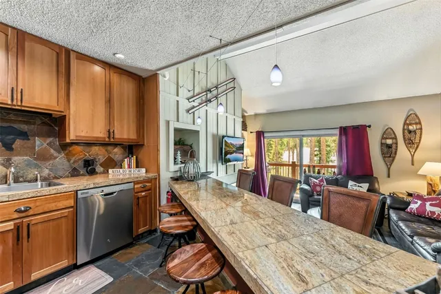 a open kitchen with stainless steel appliances granite countertop a stove a sink dishwasher and cabinets with wooden floor