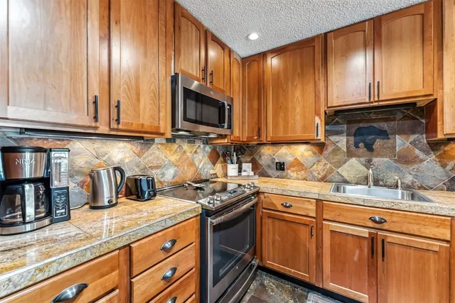 a kitchen with granite countertop cabinets stainless steel appliances and wooden cabinets