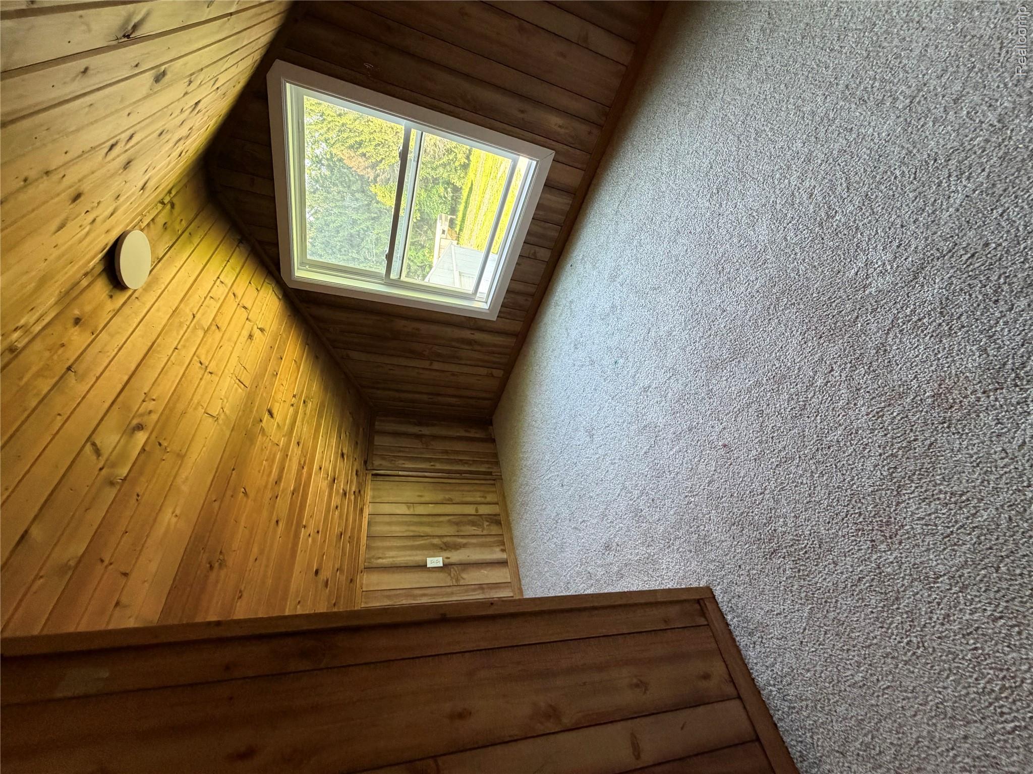 1246 House Road North Webberville, MI 48892 - Photo 12 of 22 Sloped ceiling with wood paneling, wood panel walls, recessed window with white trim, and light-colored carpet