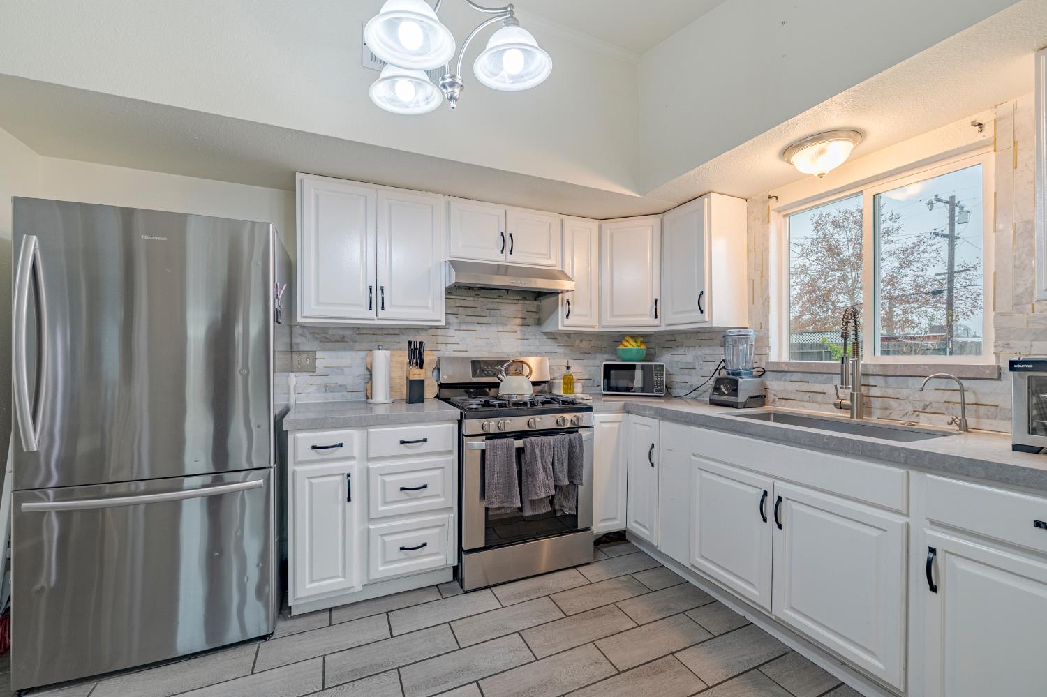 1595 East 26th Street Merced, CA 95340 - Photo 14 of 34 a kitchen with stainless steel appliances granite countertop a refrigerator a sink dishwasher a stove and white cabinets with wooden floor