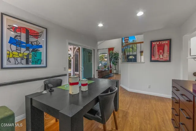 a view of a dining room with furniture one side kitchen view and wooden floor