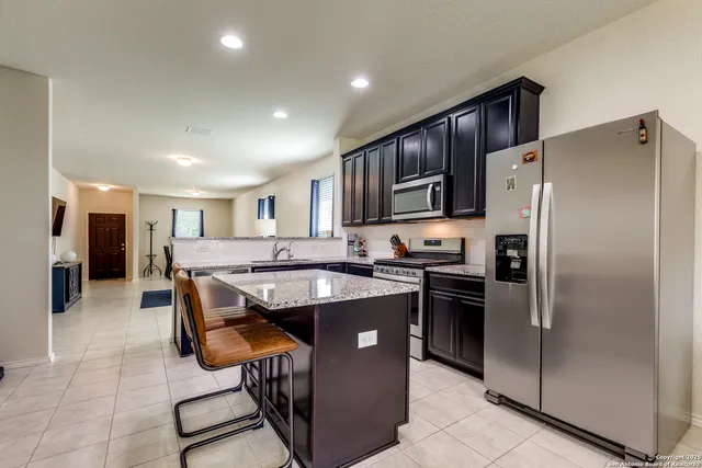 a kitchen with stainless steel appliances granite countertop a refrigerator a stove a sink and a microwave