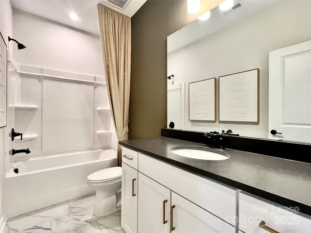 a bathroom with a granite countertop sink toilet a mirror and bathtub