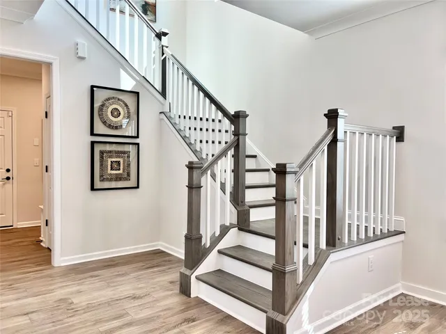 a view of staircase with lots of frames on wall and wooden floor