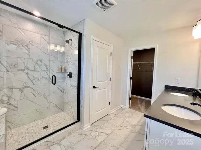a bathroom with a granite countertop sink a mirror and shower