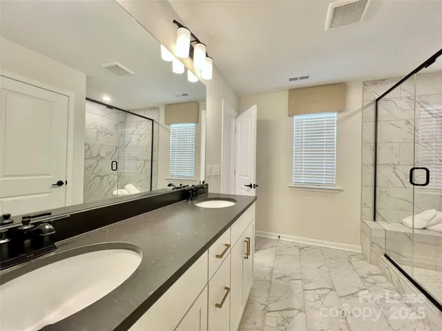 a bathroom with a granite countertop double vanity sink a mirror and a bathtub