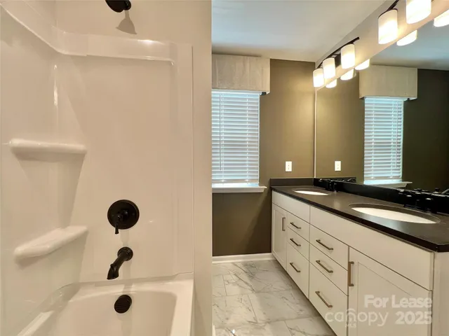a bathroom with a granite countertop sink a toilet a mirror and bathtub