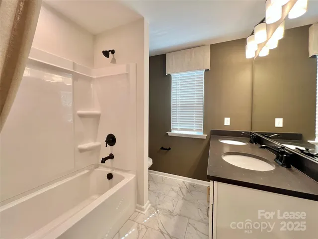 a bathroom with a bathtub sink vanity granite and shower