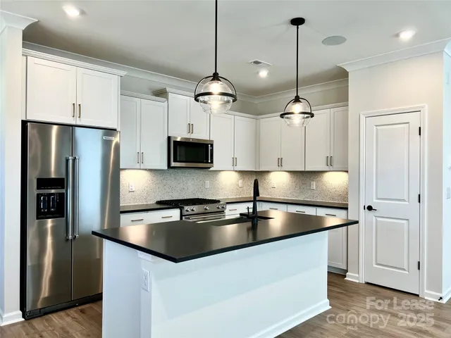 a kitchen with stainless steel appliances granite countertop a refrigerator a stove a oven and a refrigerator with wooden floor