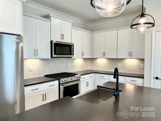 a kitchen with stainless steel appliances granite countertop a stove a sink and a microwave
