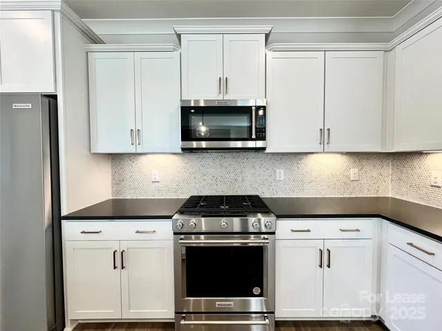 a kitchen with white cabinets and black appliances