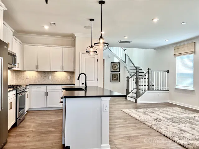 a kitchen with stainless steel appliances granite countertop a sink a stove and a wooden floor
