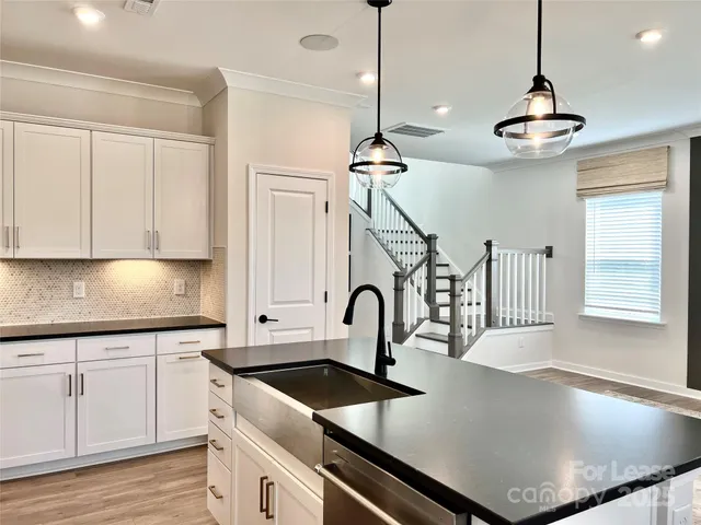 a kitchen with stainless steel appliances granite countertop a sink a stove and a wooden floors
