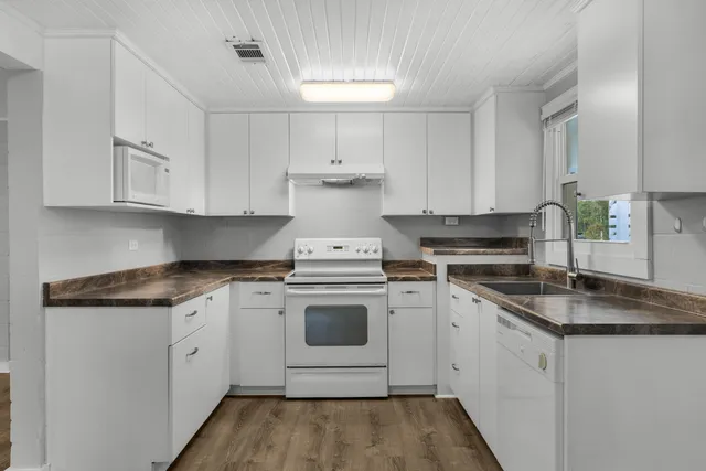 a kitchen with granite countertop white cabinets and white appliances