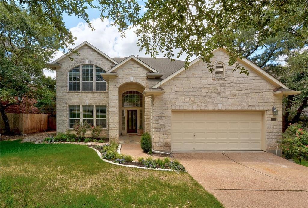 View of front of home featuring stone siding, concrete driveway, and an attached garage