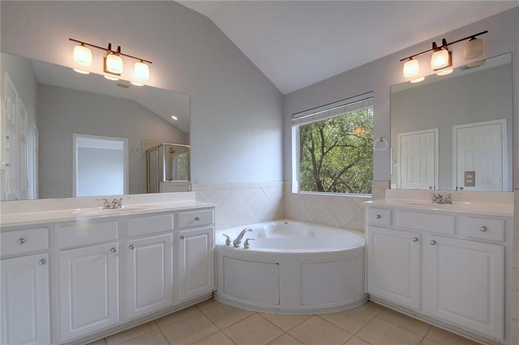13017 Titus Court Austin, TX 78732 - Photo 20 of 26 Full bath featuring lofted ceiling, a garden tub, two vanities, a shower stall, and light tile patterned flooring
