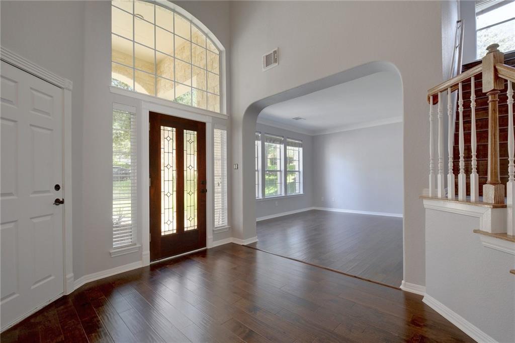 13017 Titus Court Austin, TX 78732 - Photo 5 of 26 Entryway featuring arched walkways, healthy amount of natural light, dark wood-style flooring, stairs, and ornamental molding