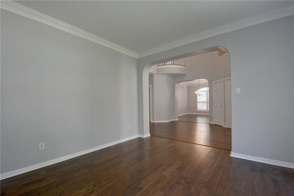 13017 Titus Court Austin, TX 78732 - Photo 7 of 26 Unfurnished room with crown molding, dark wood-style floors, arched walkways, and a chandelier
