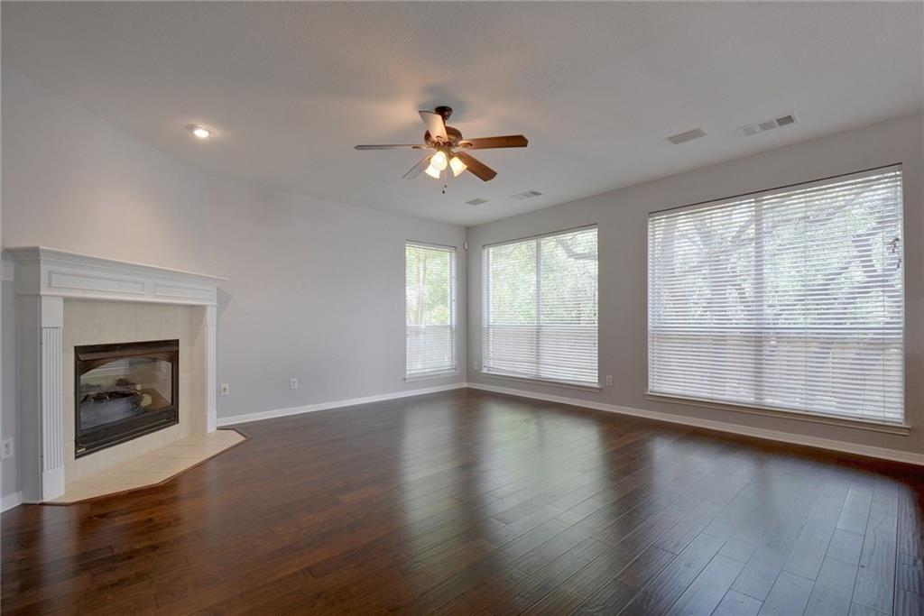 13017 Titus Court Austin, TX 78732 - Photo 10 of 26 Unfurnished living room with a tile fireplace, dark wood-style floors, a ceiling fan, and recessed lighting