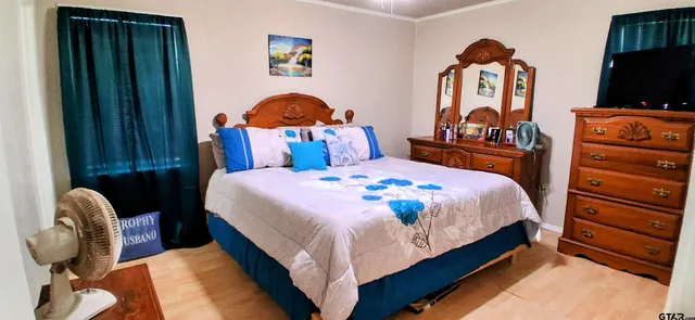 a bedroom with bed and a flat tv screen on dresser