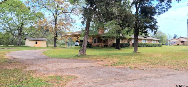 a view of a house with a yard and palm trees