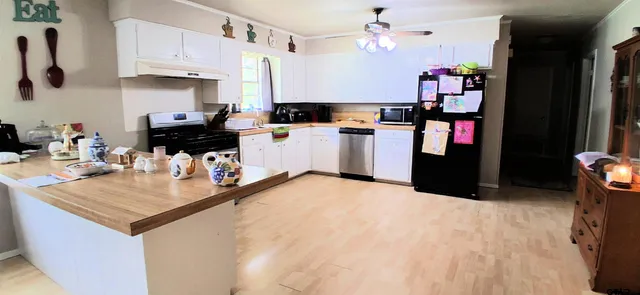 a kitchen with kitchen island a white counter top space and stainless steel appliances