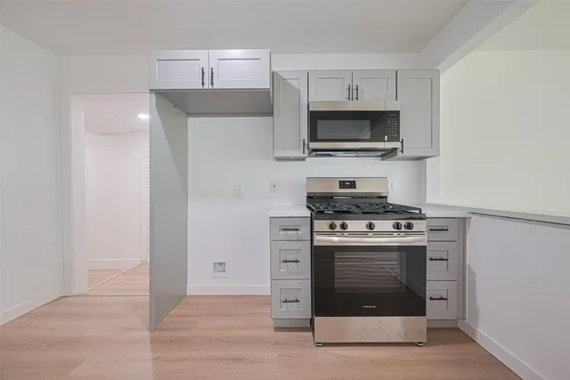 a kitchen with stainless steel appliances a stove a microwave and white cabinets