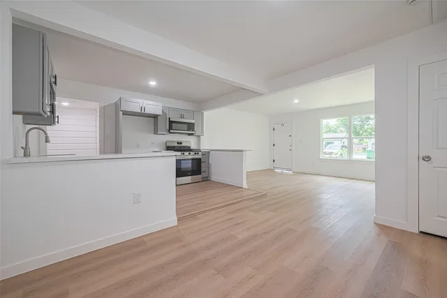 a view of a kitchen with a sink dishwasher cabinets and wooden floor