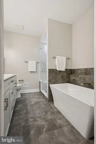 a spacious bathroom with a tub sink and mirror