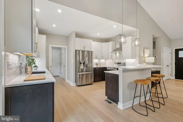 a kitchen with stainless steel appliances kitchen island granite countertop a refrigerator a stove a sink and a dining table with wooden floor