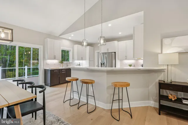 a kitchen with stainless steel appliances kitchen island granite countertop a table chairs sink and cabinets