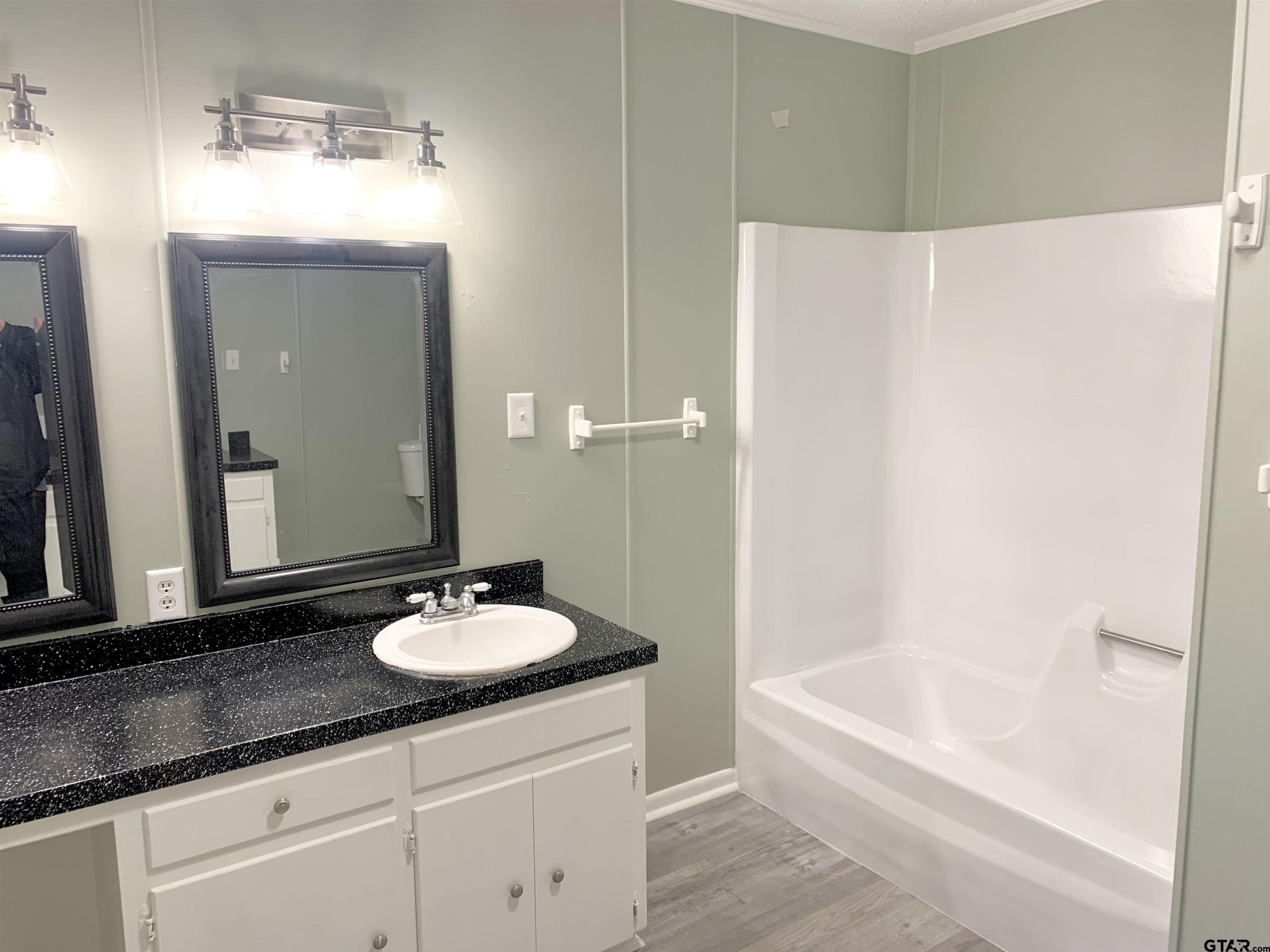 901 Cliff Street Quitman, TX 75783 - Photo 16 of 16 a bathroom with a granite countertop sink a mirror and a bathtub