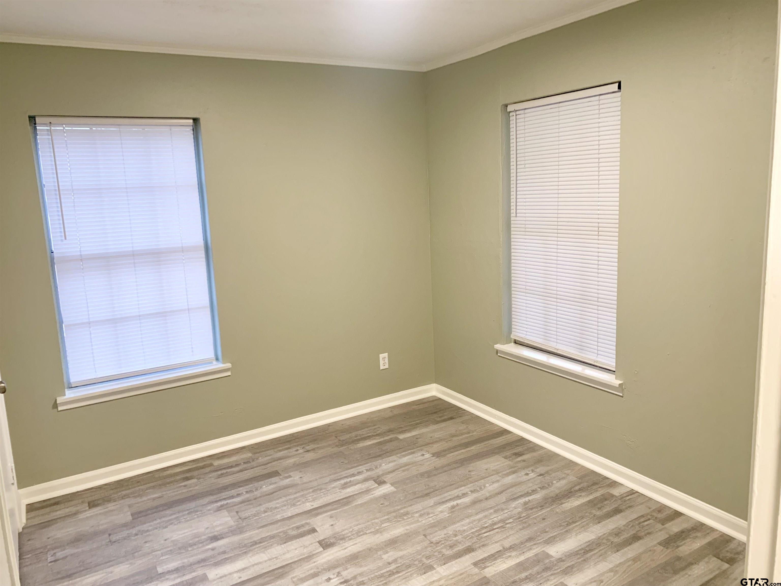 901 Cliff Street Quitman, TX 75783 - Photo 7 of 16 a view of an empty room with wooden floor and a window