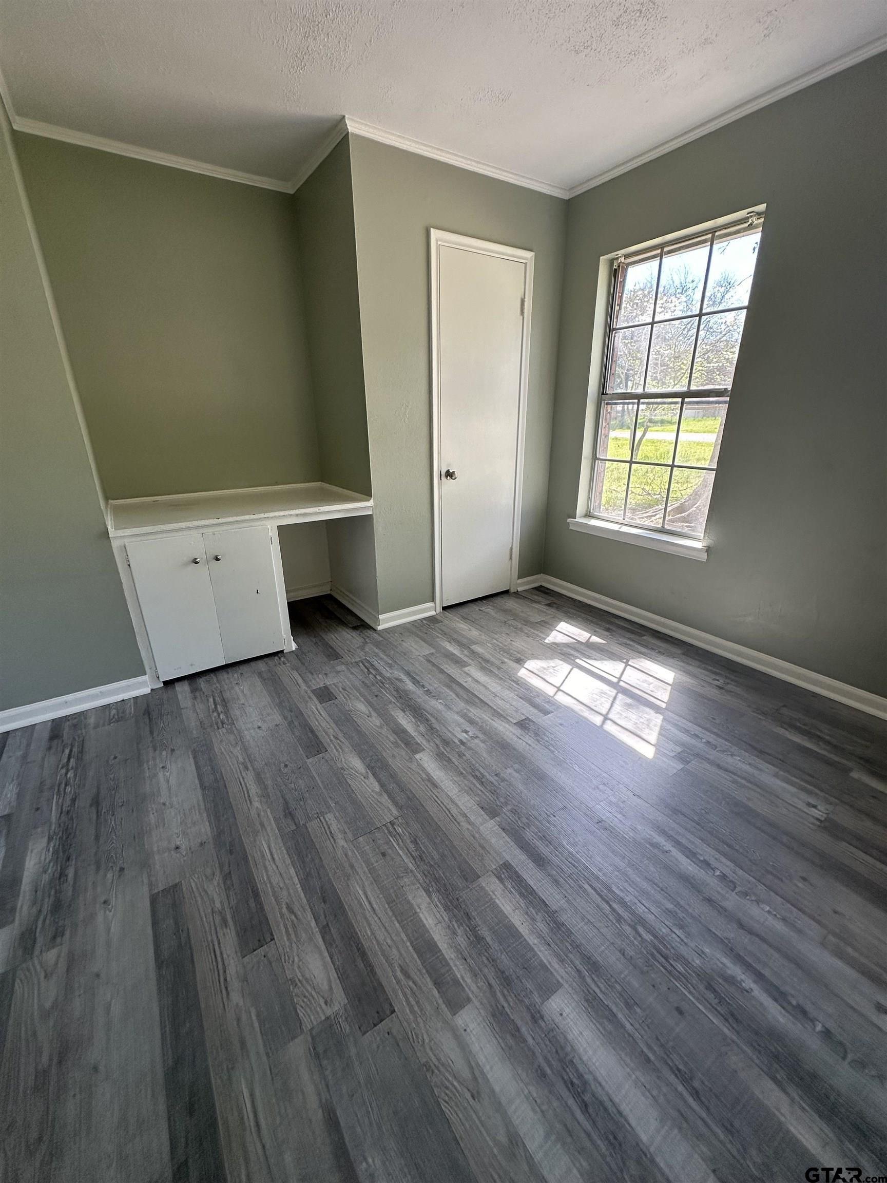 901 Cliff Street Quitman, TX 75783 - Photo 8 of 16 an empty room with wooden floor and windows