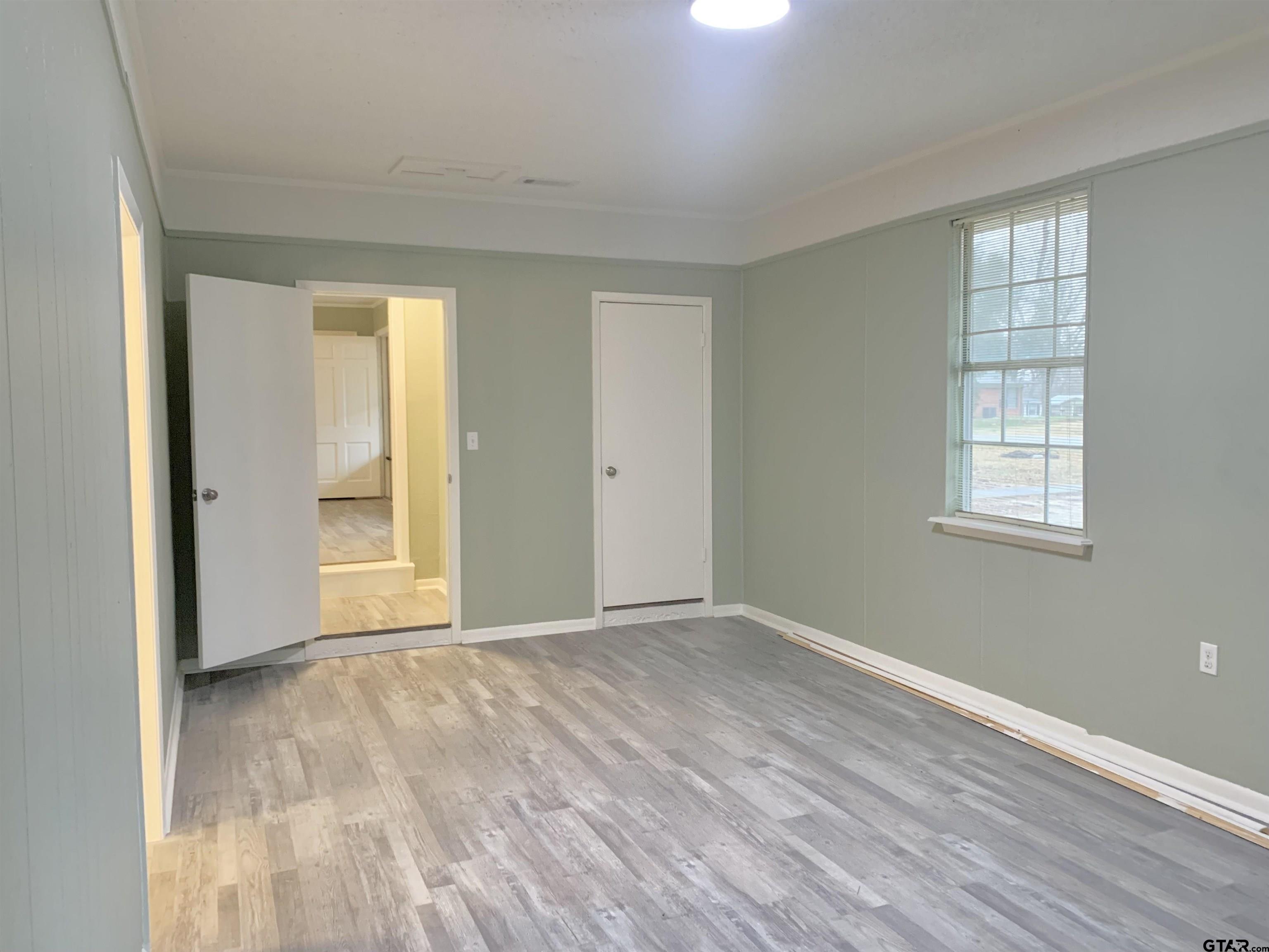 901 Cliff Street Quitman, TX 75783 - Photo 9 of 16 a view of an empty room with wooden floor and a window