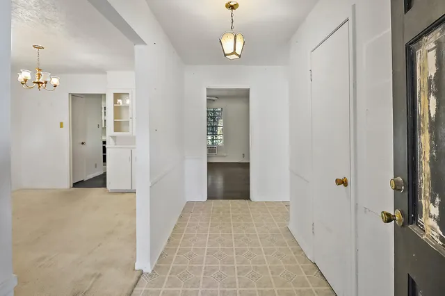 a view of a hallway with wooden floor and chandelier