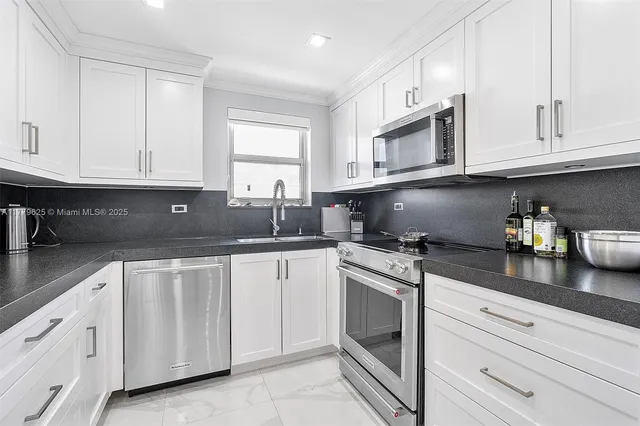 a kitchen with granite countertop white cabinets stainless steel appliances and sink